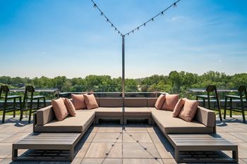 A wooden deck with a couch and a table with a view of a lake.